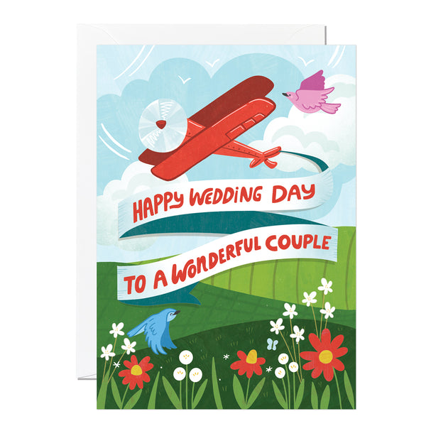 A wedding card featuring an illustration of a plane and a banner that says 'happy wedding day to a wonderful couple'.