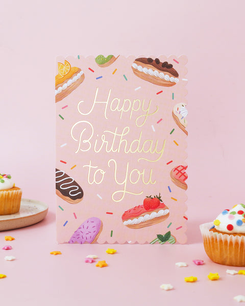 Birthday card with colorful pastries and 'Happy Birthday to You' text on a pink background