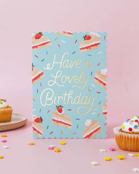 Birthday card with cake illustrations and 'Have a Lovely Birthday' text on a pink background