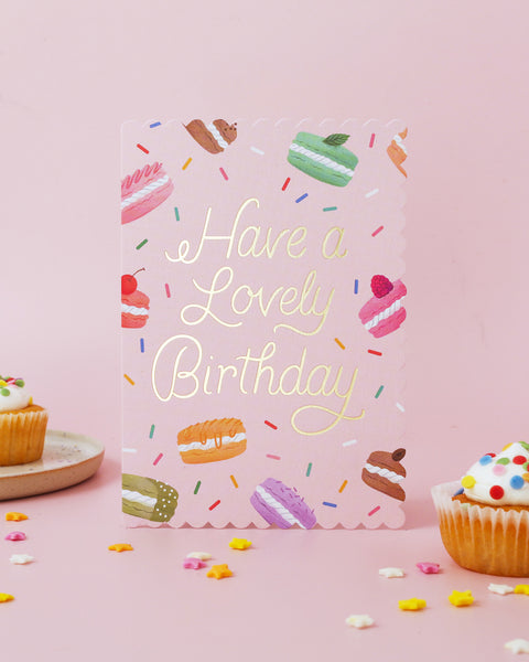 Birthday card with macaron illustrations and 'Have a Lovely Birthday' text on a pink background