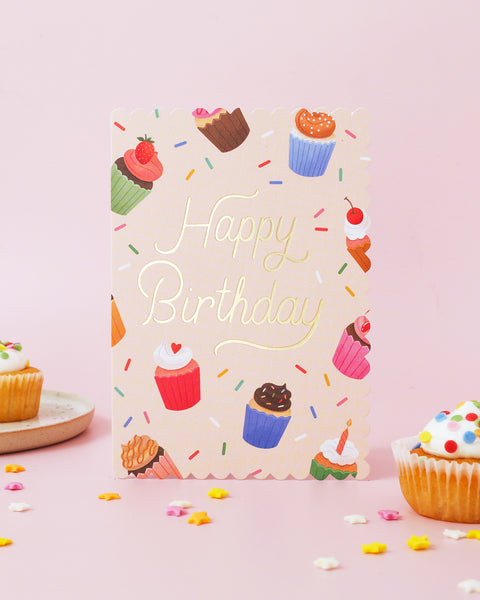 Birthday card with cupcake illustrations and 'Happy Birthday' text on a pink background