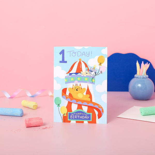 A colourful 1st birthday card featuring an illustration of a helter skelter with cartoon animals and the text '1st Today!' along with a 'Happy Birthday' message.