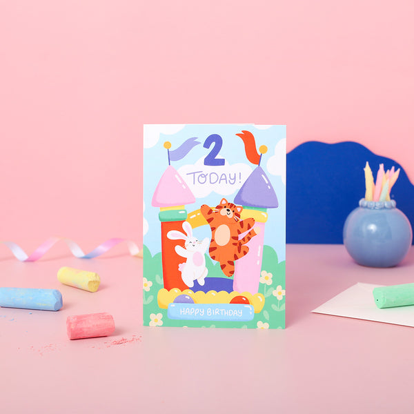 A colourful 2nd birthday card with a tiger and a rabbit on a bouncy castle.