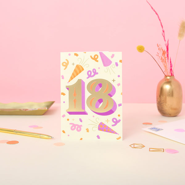 An 18th birthday card with gold foil details, featuring a colourful party-themed design with the number 18 and decorative elements like party hats and streamers.