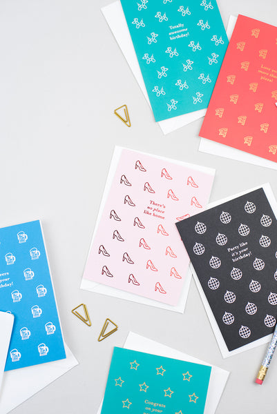 A pink birthday card featuring small illustrations of a crown printed with gold foil and a greeting reading 'yaaasss birthday queen'