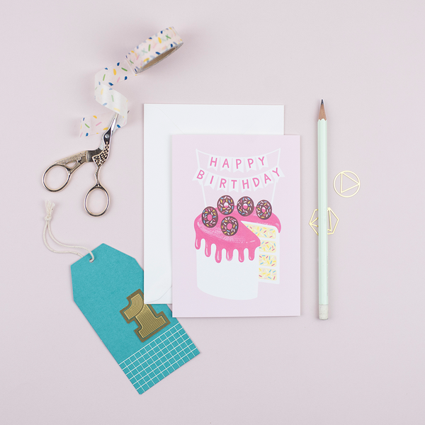 A birthday card featuring a hand-painted birthday cake with doughnuts and confetti sponge