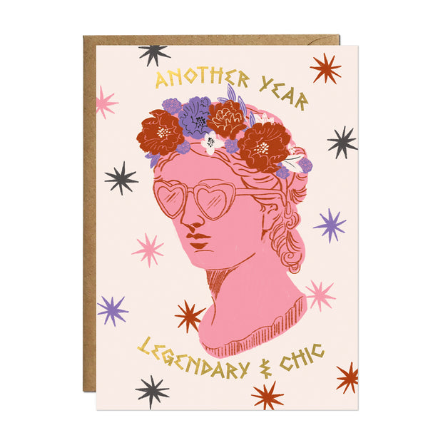 A fashion-forward birthday card featuring a pink classical bust wearing heart-shaped sunglasses and a rich crown of autumn-toned peonies and dahlias.