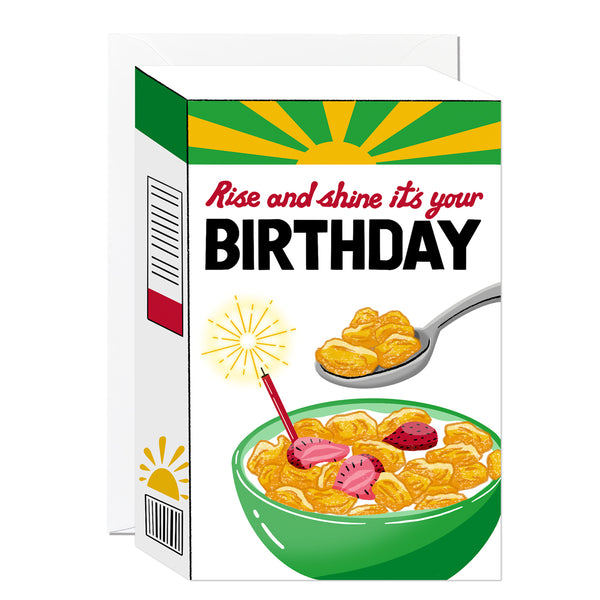 A die-cut birthday card illustrating a vibrant sunburst-themed cereal box with a crisp bowl of cornflakes, fresh strawberries, and a burning candle.