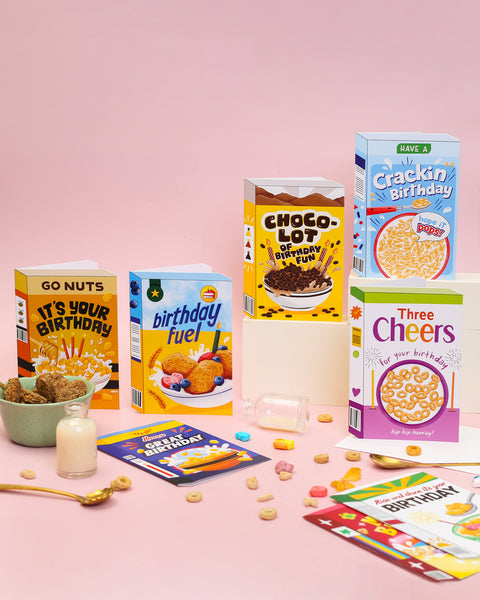 Assorted cereal boxes with birthday-themed designs on a pink background