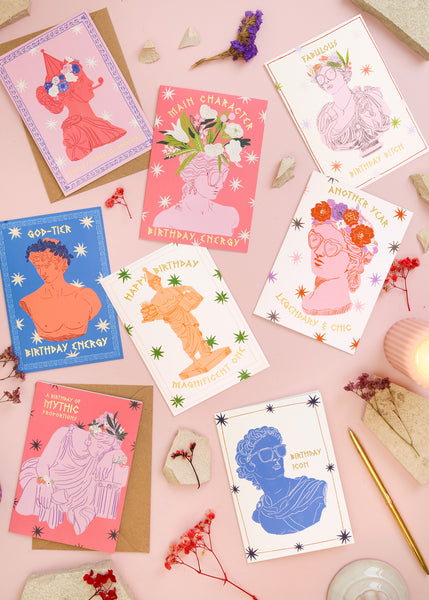 Collection of colorful greeting cards with artistic designs on a pink surface.