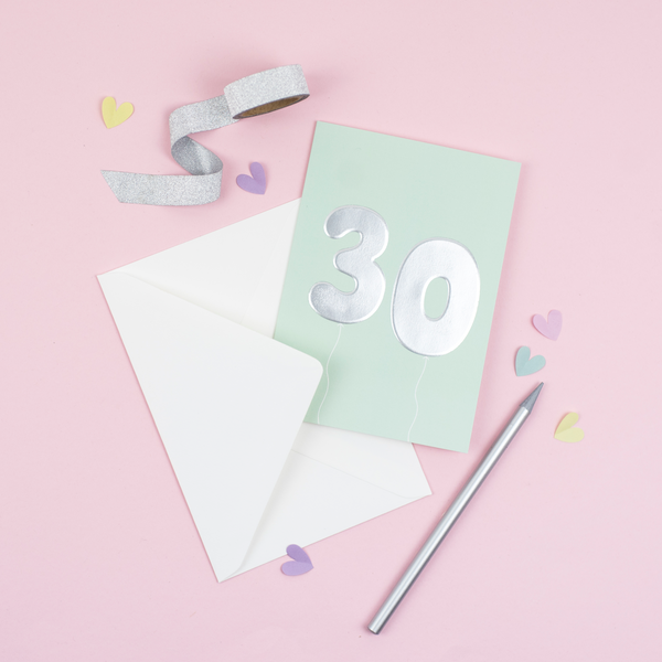 A 30th birthday card with birthday balloons that have been printed with an embossed silver foil on a mint greeting card
