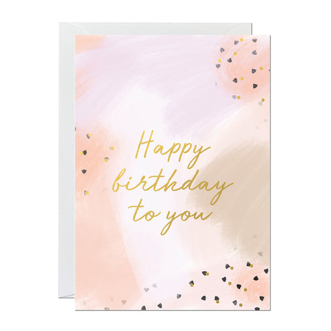 A birthday card with gold foiled lettering reading 'happy birthday to you' printed on a hand-painted canvas background.