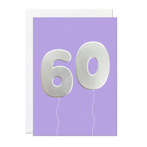 A 60th birthday card featuring big helium balloons printed with an embossed silver foil on a purple card.