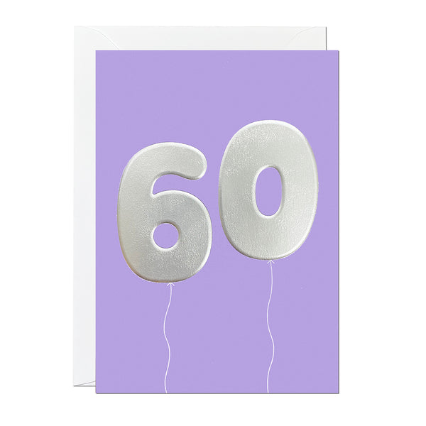 A 60th birthday card featuring big helium balloons printed with an embossed silver foil on a purple card.