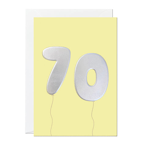 A yellow 70th birthday card featuring birthday balloons that have been printed with an embossed silver foil