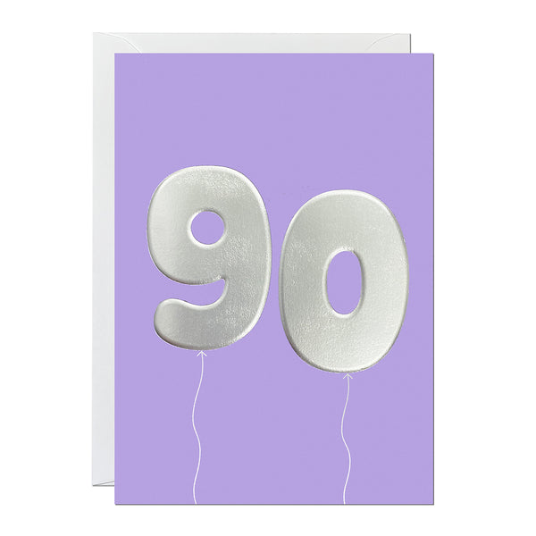 A 90th birthday card featuring big helium balloons printed with an embossed silver foil on a purple card.