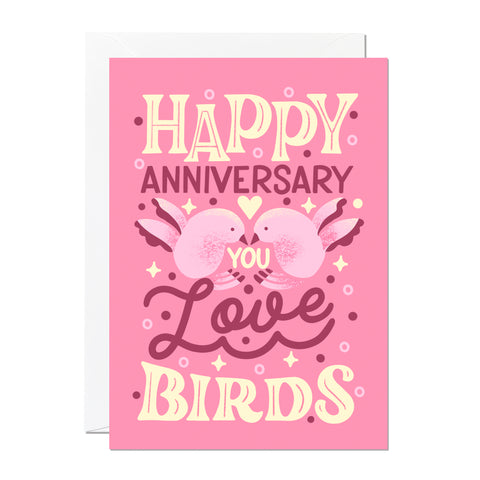 This is an anniversary card by Ricicle Cards. It reads 'happy anniversary you love birds' and features hand-lettering and illustration set on a light pink background. 