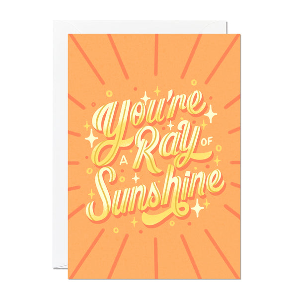 This greeting card features hand-lettering by Roselly Monegro and says 'you're a ray of sunshine'. It's set on a orange and yellow background and is printed in the UK.
